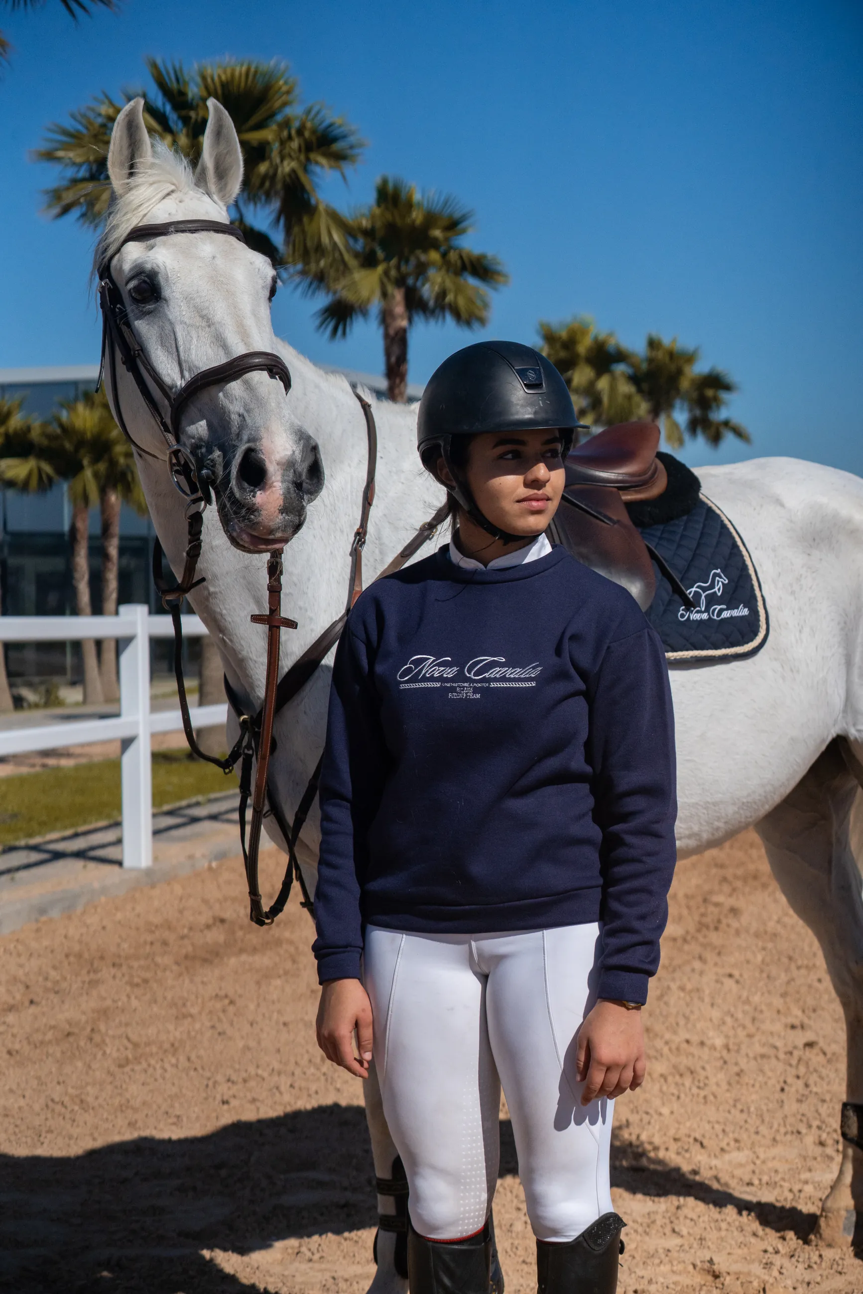 Cavaliere menant un cheval gris devant les palmiers